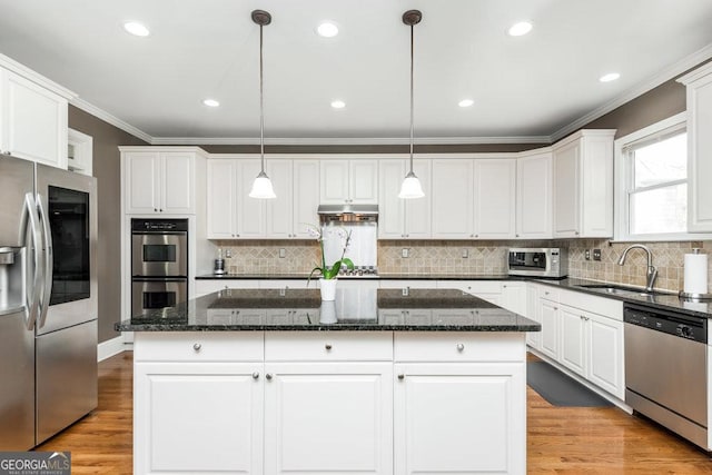 kitchen with a center island, sink, stainless steel appliances, and hanging light fixtures