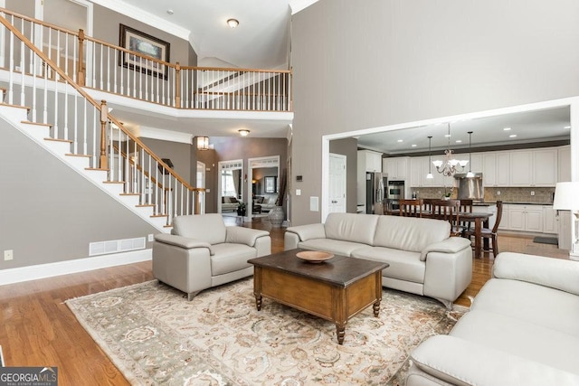 living room featuring a towering ceiling, light hardwood / wood-style floors, and ornamental molding