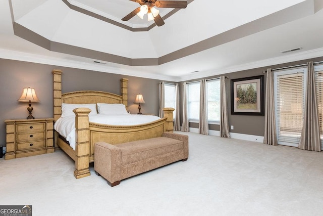 carpeted bedroom with ceiling fan, a raised ceiling, and ornamental molding