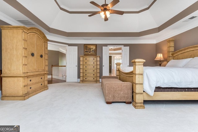 carpeted bedroom featuring a raised ceiling, ceiling fan, and ornamental molding