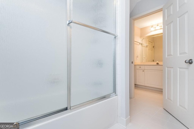 bathroom featuring tile patterned flooring, vanity, and enclosed tub / shower combo