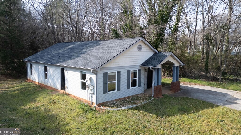 view of front facade with a front lawn, driveway, and a shingled roof