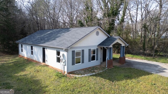 view of front facade with a front lawn, driveway, and a shingled roof