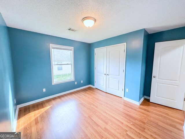 bedroom with wood finished floors, visible vents, and baseboards