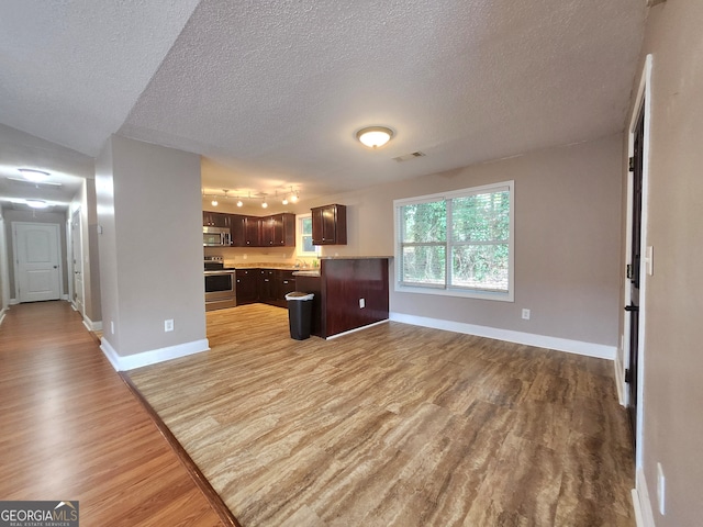 kitchen featuring dark brown cabinets, stainless steel appliances, a textured ceiling, and hardwood / wood-style flooring