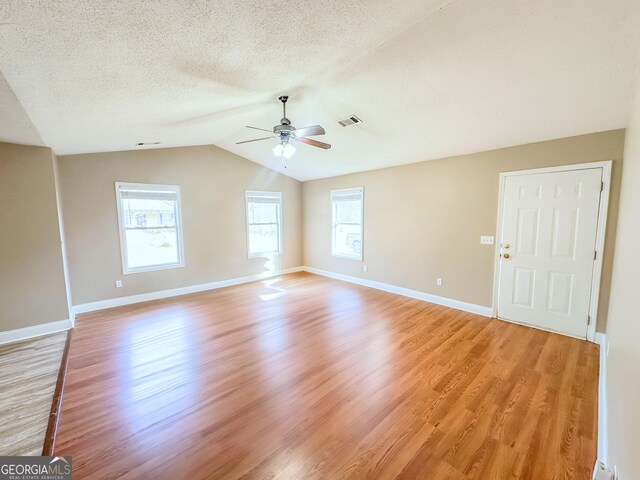 unfurnished living room with plenty of natural light, wood-type flooring, and vaulted ceiling