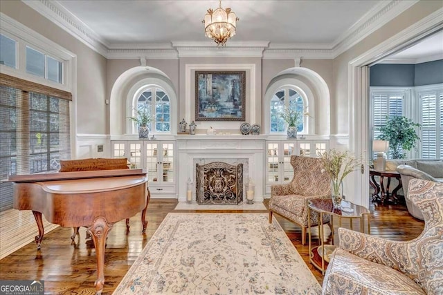 sitting room featuring a notable chandelier, wood-type flooring, a high end fireplace, and crown molding