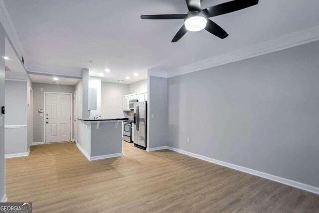 kitchen with a breakfast bar area, white cabinetry, stainless steel appliances, and light wood-type flooring