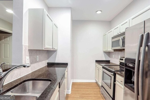 kitchen with white cabinetry, sink, tasteful backsplash, dark stone counters, and appliances with stainless steel finishes