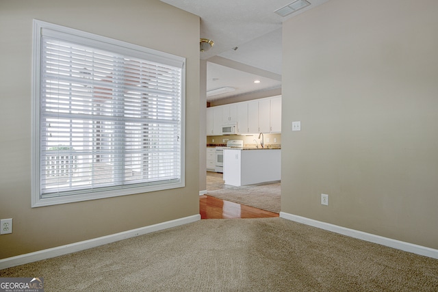 unfurnished living room featuring light carpet and sink