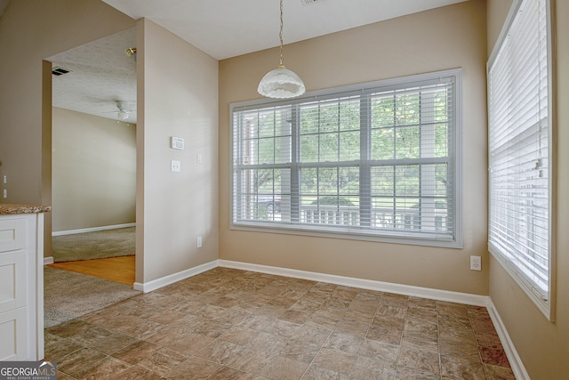 carpeted empty room featuring ceiling fan, a healthy amount of sunlight, and a textured ceiling