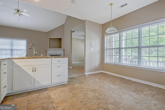 kitchen featuring sink, white cabinets, vaulted ceiling, hanging light fixtures, and ceiling fan