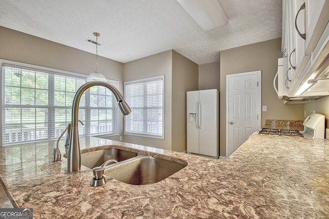 kitchen featuring a textured ceiling, a healthy amount of sunlight, white appliances, and sink