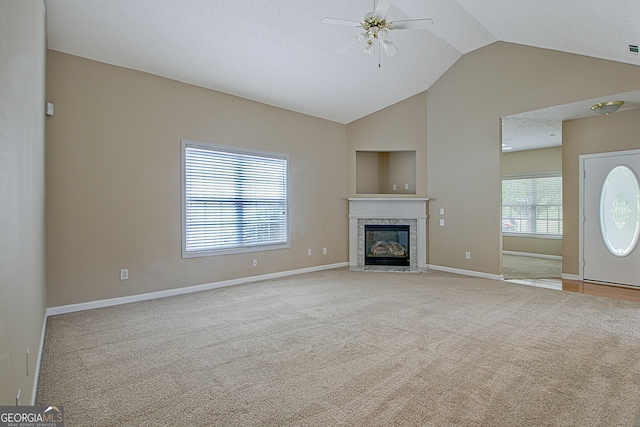 unfurnished living room with lofted ceiling, ceiling fan, light colored carpet, and a textured ceiling