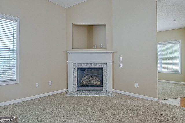 unfurnished living room with a textured ceiling, a fireplace, and carpet