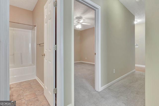 hall featuring light carpet and a textured ceiling