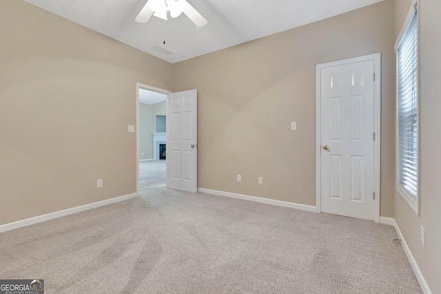 unfurnished bedroom featuring ceiling fan, light carpet, and multiple windows