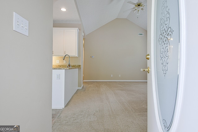 interior space featuring sink, lofted ceiling, white cabinetry, light colored carpet, and ceiling fan