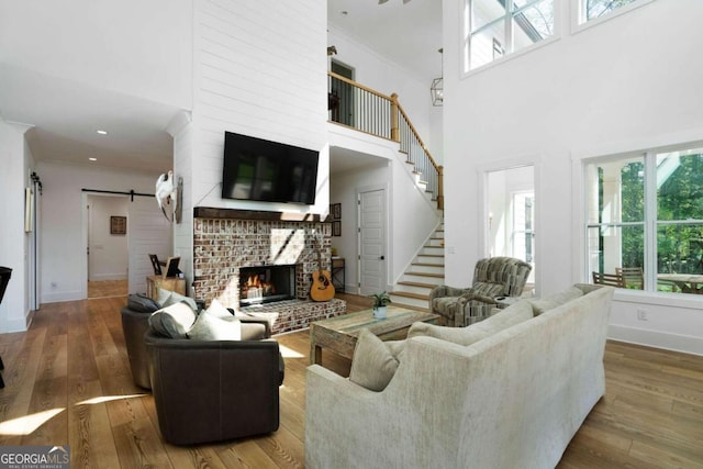 living room with a brick fireplace, a high ceiling, plenty of natural light, and a barn door