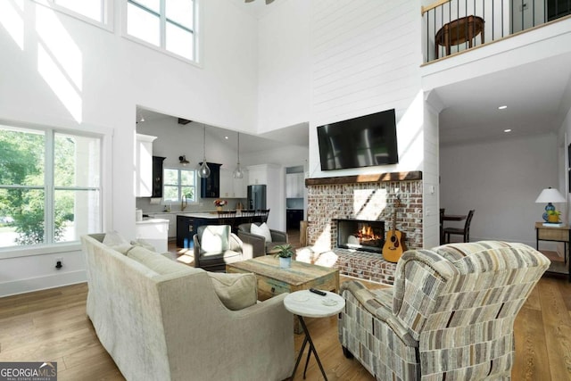 living room with a fireplace, light wood-type flooring, and a high ceiling