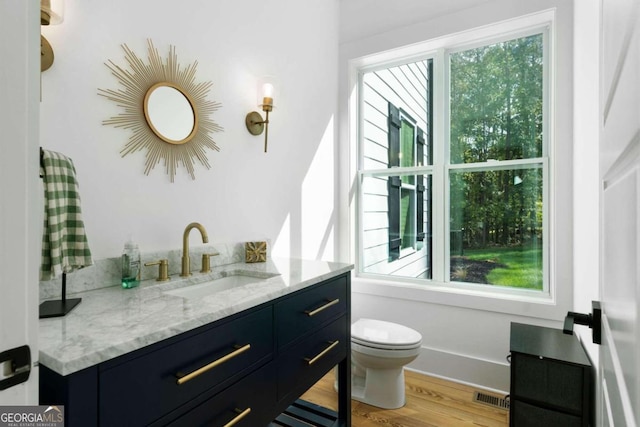 bathroom with a wealth of natural light, hardwood / wood-style floors, vanity, and toilet