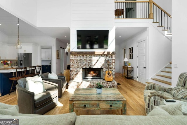 living room with a towering ceiling, light hardwood / wood-style floors, and a fireplace