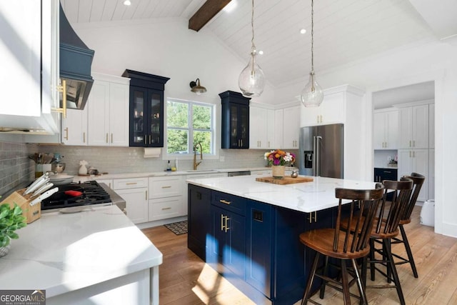 kitchen featuring light hardwood / wood-style floors, a center island, beam ceiling, white cabinetry, and appliances with stainless steel finishes