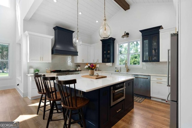 kitchen featuring a healthy amount of sunlight, premium range hood, a center island, and stainless steel appliances