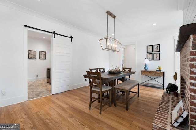 dining space featuring an inviting chandelier, crown molding, hardwood / wood-style floors, and a barn door