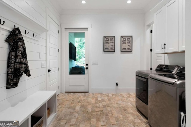 clothes washing area with cabinets, light wood-type flooring, and washer and clothes dryer