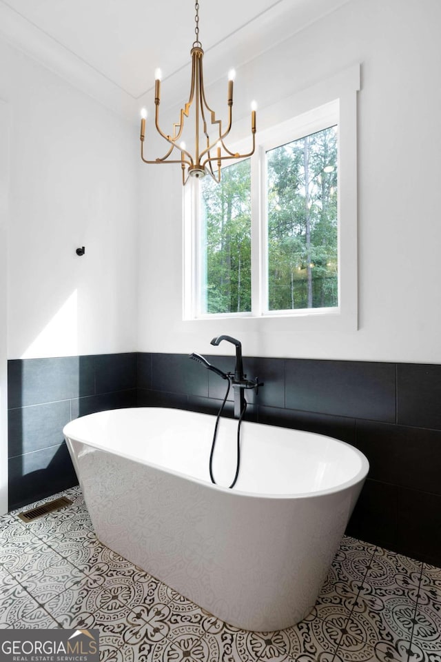 bathroom featuring ornamental molding, tile walls, tile patterned flooring, and a bath