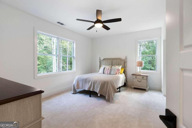 bedroom with ceiling fan, light carpet, and multiple windows