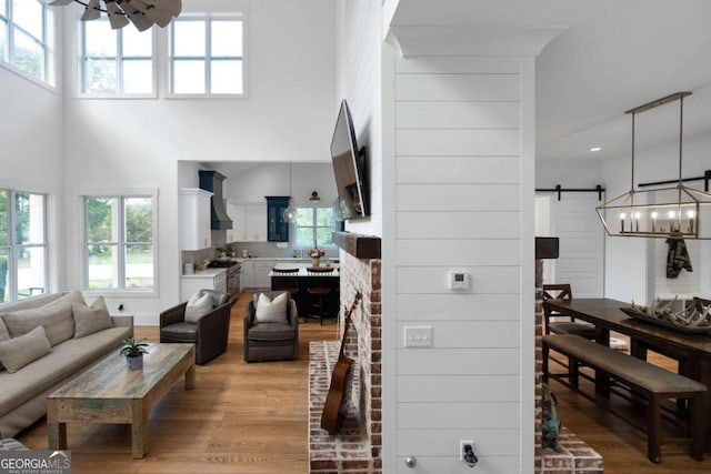 living room featuring light hardwood / wood-style flooring, a towering ceiling, and a barn door