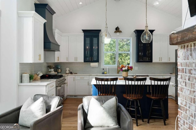 kitchen featuring white cabinetry, high end stainless steel range, high vaulted ceiling, backsplash, and pendant lighting