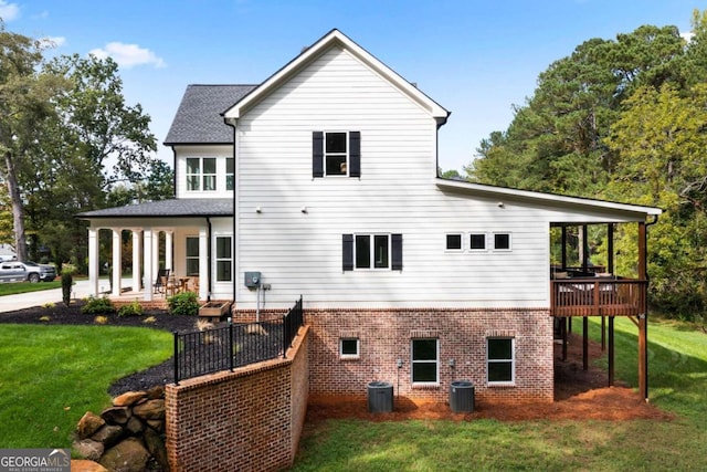 rear view of property featuring central AC unit, a deck, and a lawn