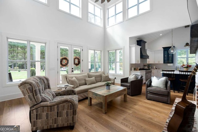 living room featuring french doors, light wood-type flooring, and a towering ceiling