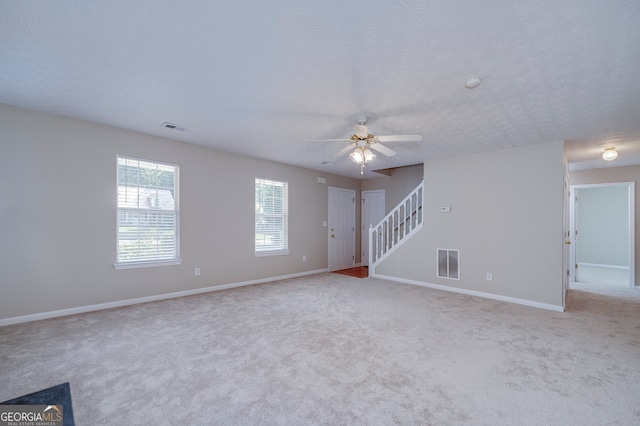 carpeted spare room with a textured ceiling and ceiling fan