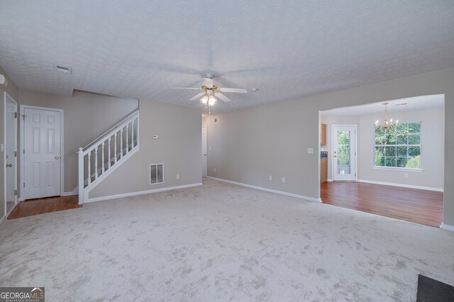 unfurnished living room featuring hardwood / wood-style floors, ceiling fan with notable chandelier, and a textured ceiling