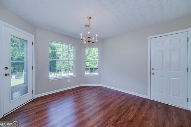 unfurnished dining area with dark hardwood / wood-style flooring, a textured ceiling, and plenty of natural light