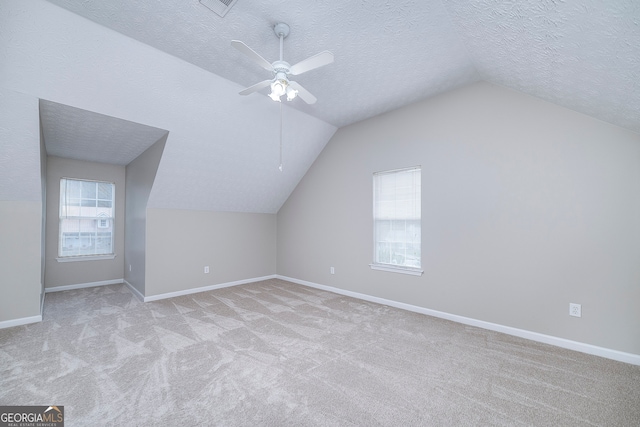 bonus room featuring ceiling fan, light colored carpet, a textured ceiling, and vaulted ceiling