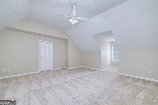 additional living space with lofted ceiling, a textured ceiling, light carpet, and ceiling fan