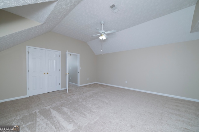 bonus room with light colored carpet, a textured ceiling, ceiling fan, and vaulted ceiling