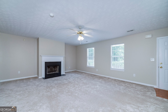 unfurnished living room featuring a textured ceiling, light carpet, and ceiling fan