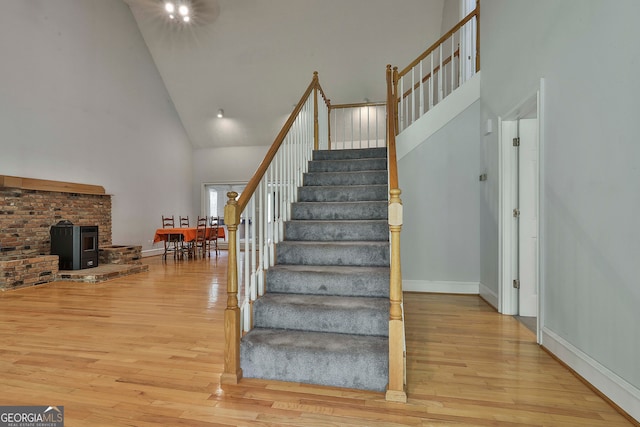 staircase with a fireplace, hardwood / wood-style floors, and high vaulted ceiling