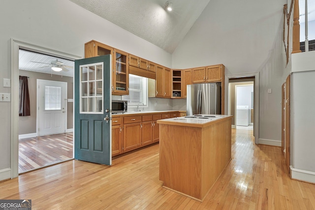 kitchen with light wood-type flooring, a kitchen island, high vaulted ceiling, stainless steel appliances, and ceiling fan