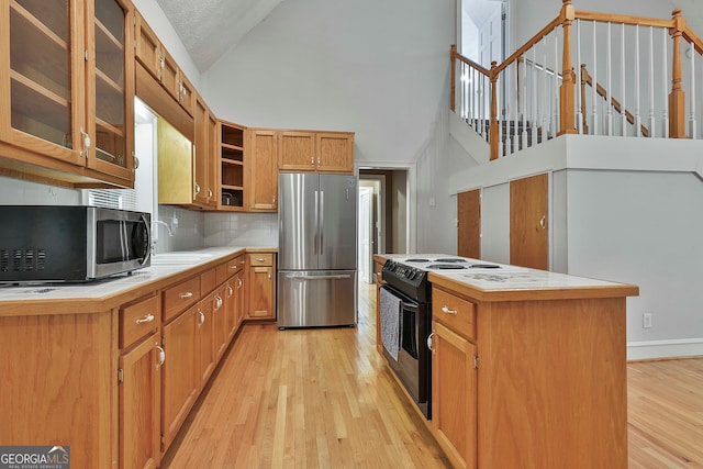 kitchen with a textured ceiling, a center island, sink, light hardwood / wood-style flooring, and appliances with stainless steel finishes