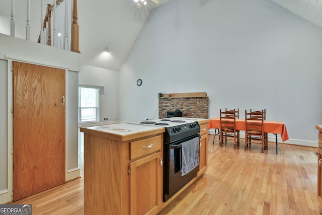 kitchen with light hardwood / wood-style floors, black electric range, a kitchen island, high vaulted ceiling, and tile countertops