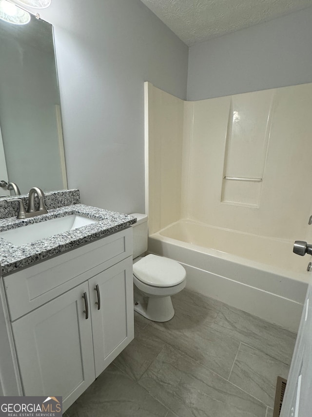 full bathroom with vanity, a textured ceiling, toilet, and washtub / shower combination