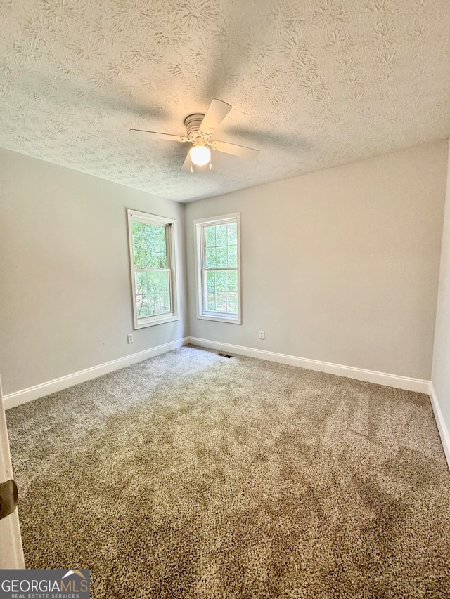 unfurnished room featuring ceiling fan, carpet floors, and a textured ceiling