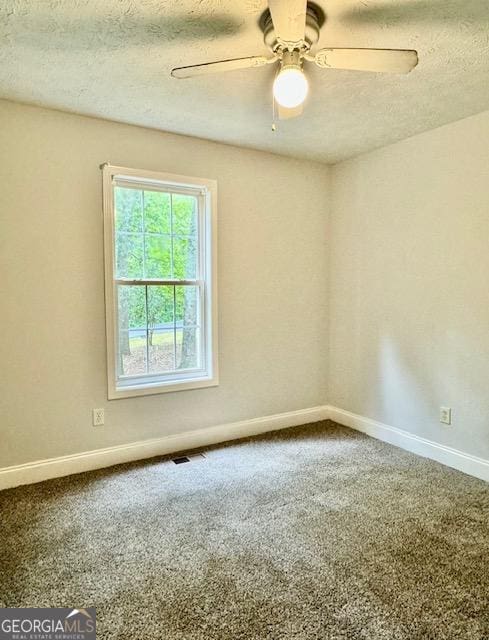 empty room featuring ceiling fan, carpet flooring, and a textured ceiling